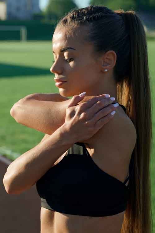 早上，一個女孩在體育場進行上半身熱身運動。.